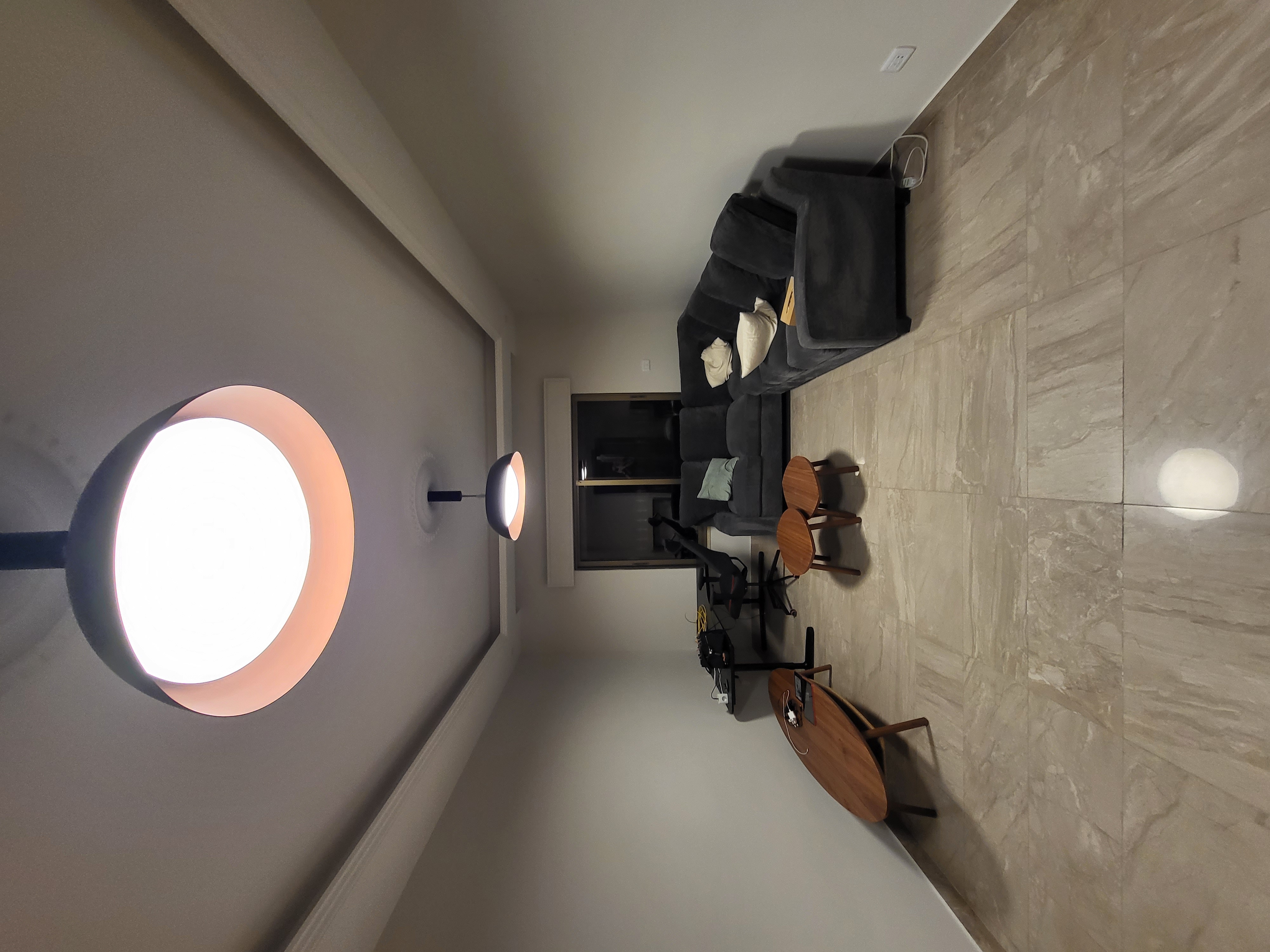 Apartment living room after renovation — clean white walls, statement pendant and new floor