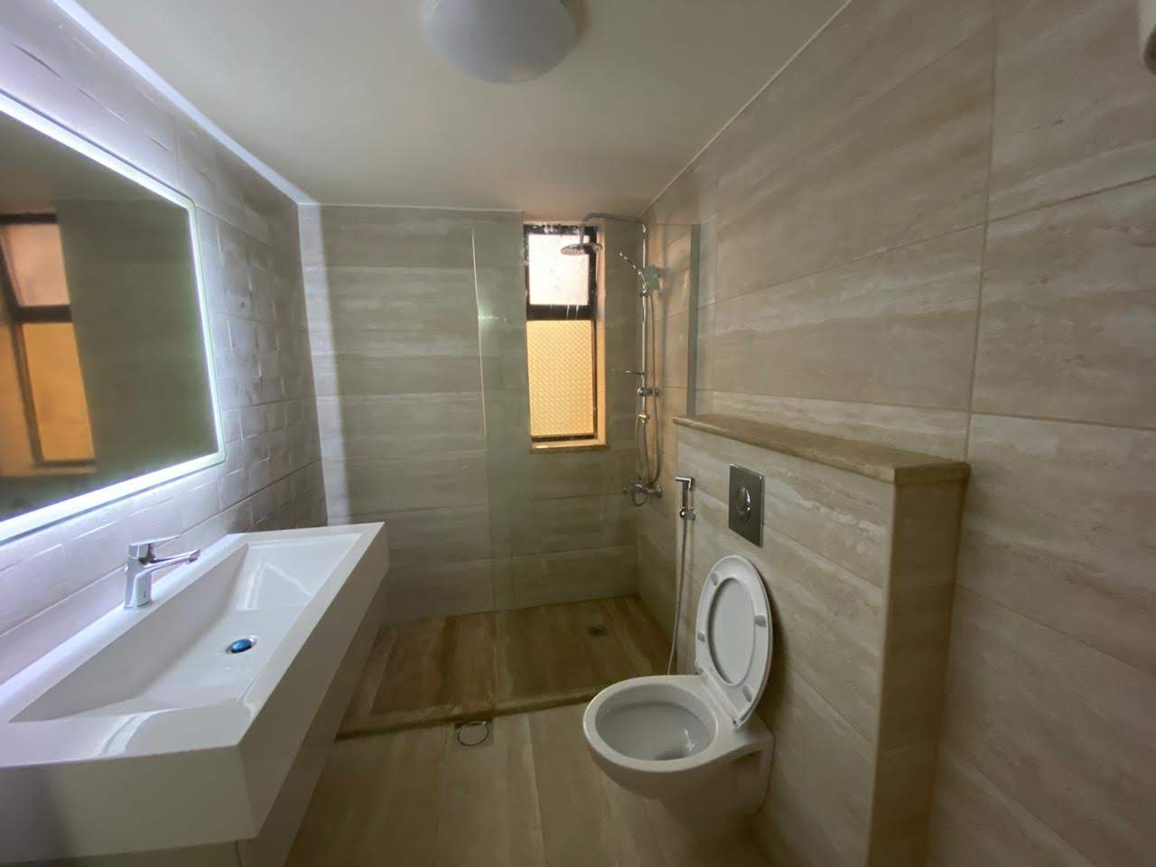 Bathroom after renovation — modern tiling, wall-hung WC and backlit mirror