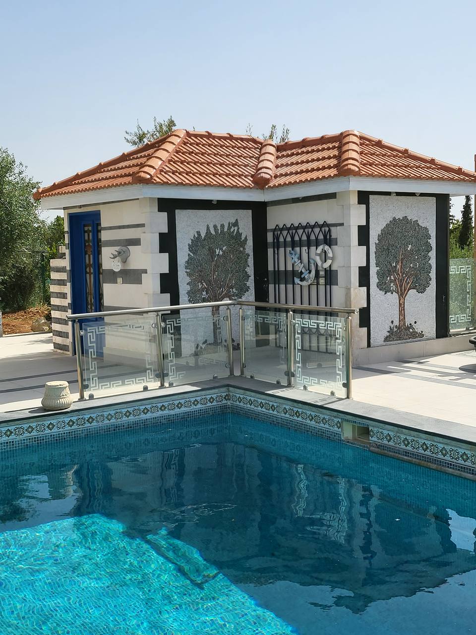 Pool pavilion — ornate stone facade, mosaic panels and glass balustrade