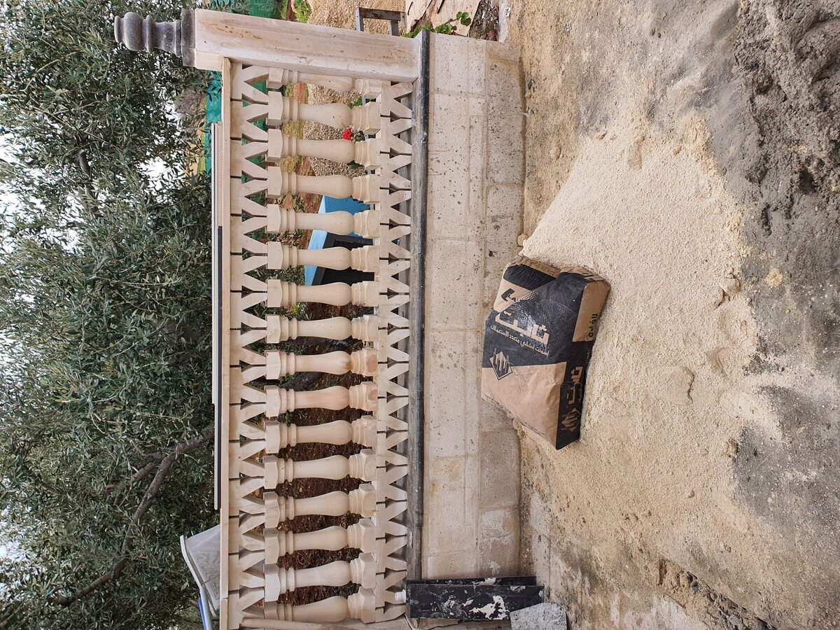 Ornamental limestone balustrade being installed — balusters set and cement mortar applied