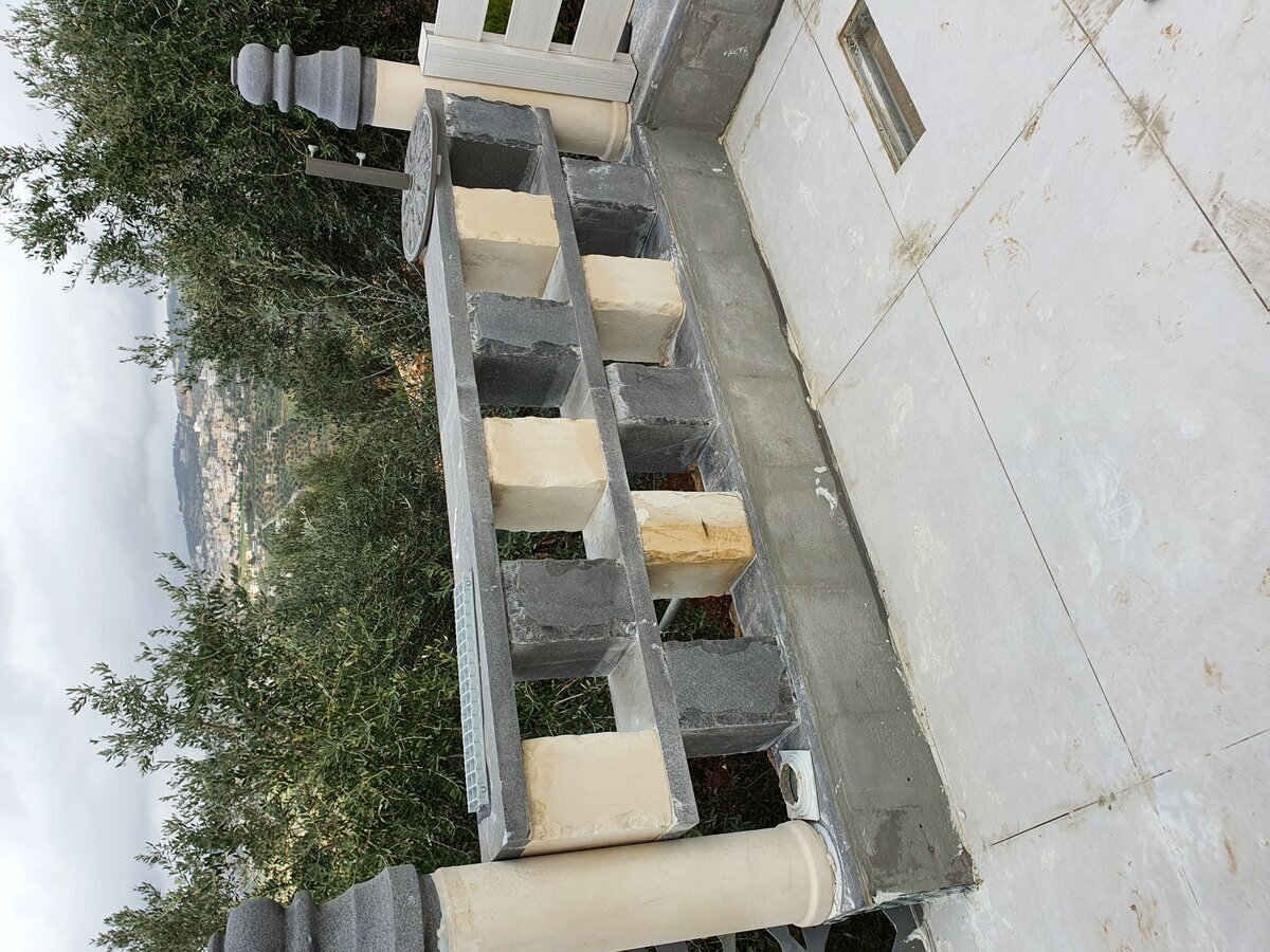 Ornamental balustrade masonry in progress — block coursework and column caps being fitted