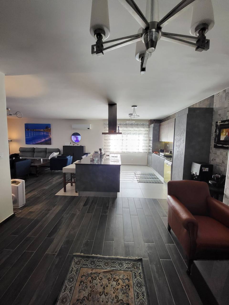Open-plan living room and kitchen — completed interior fit-out with dark wood-effect flooring