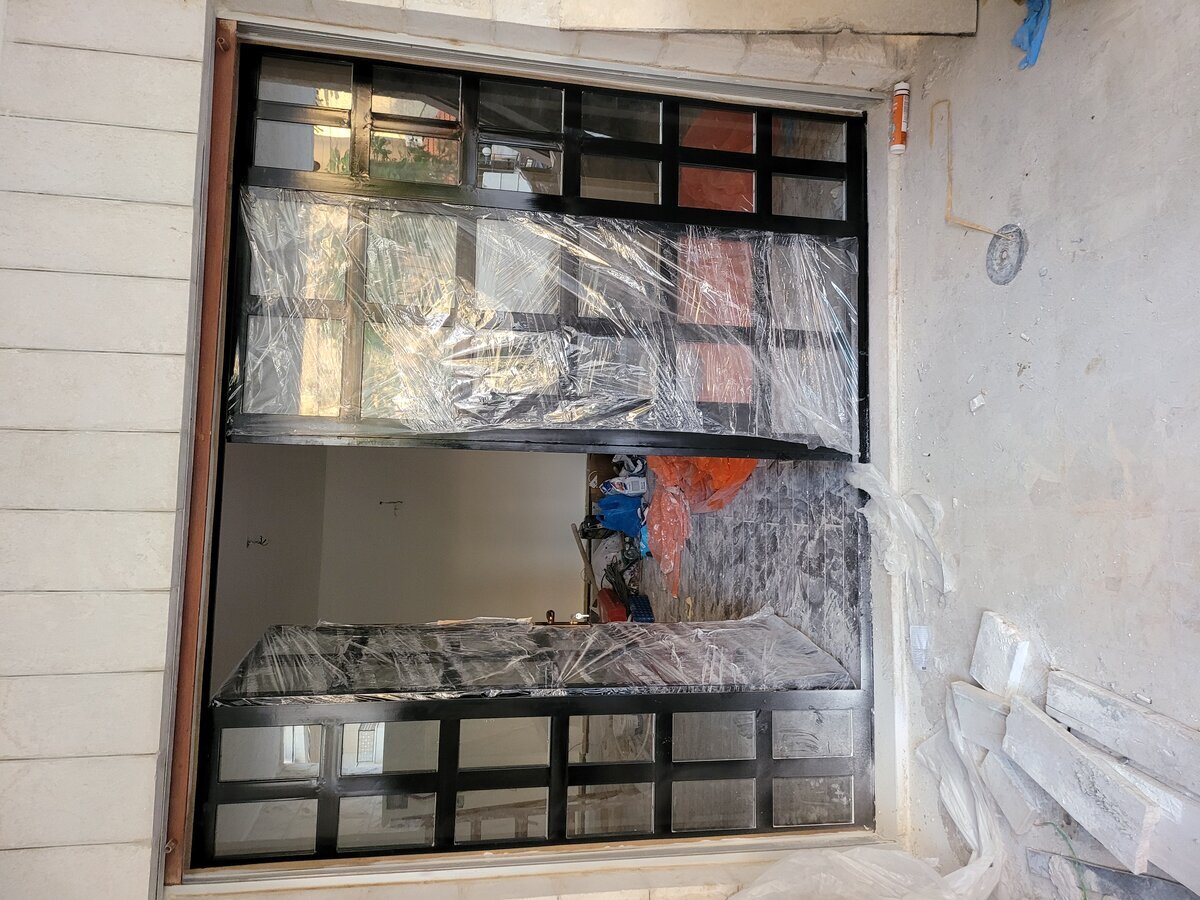 New terrace entrance — bespoke black steel and glass door being installed, wrapped for protection