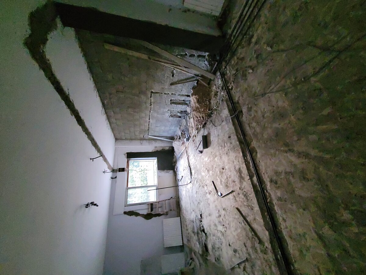 New kitchen and living zone being formed — partition wall removed, fresh concrete beam visible overhead